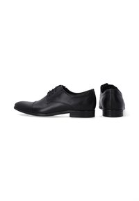 Zwarte leren dresschoenen met een glad oppervlak, ronde neus en minimale stiksels. Voorzien van een lage hak en platte veters. Strak ontwerp.