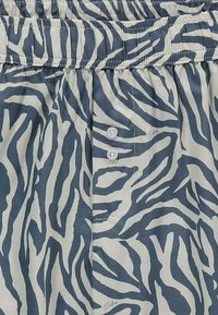 Lettere shorts med et blåt og hvidt zebra-stribemønster, med en elastisk talje og tre hvide knapper på forsiden.