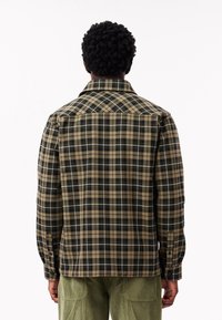 Randig skjorta i mörkgrön, beige och svart, med krage och knäppte manschetter. Tyget verkar mjukt och texturerat.