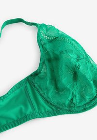 Bralette verde in pizzo con una base in raso liscio, sovrapposizione di coppe in pizzo floreale, spalline regolabili e una fusciacca leggermente testurizzata.