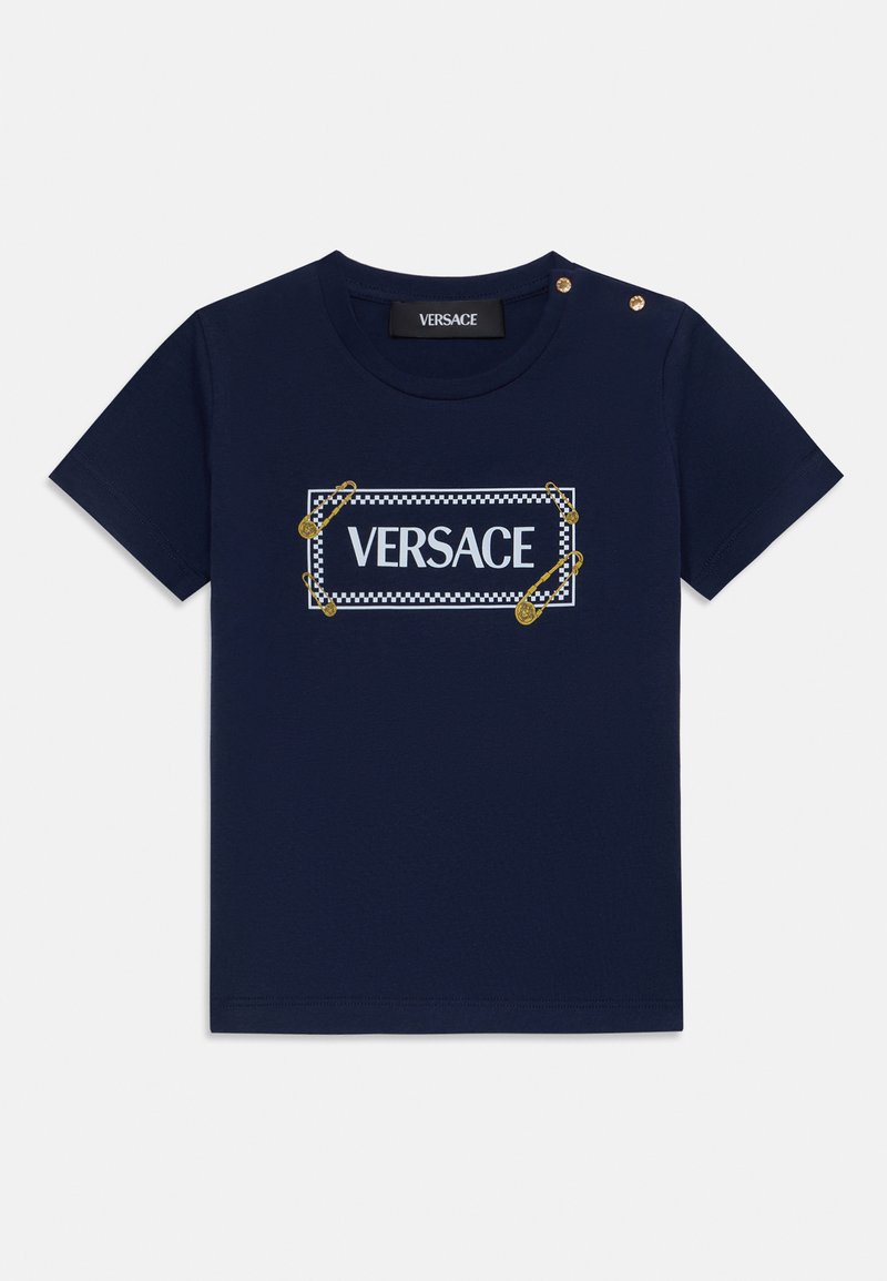 Marinblå bomulls-t-shirt med rund halsringning, prydd med en vit "VERSACE"-logotyp inramad av ett rutmönster, accentuerad med gyllene säkerhetsnålar.