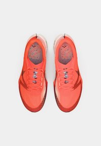 Lysende orange sportssko med en tekstureret overdel, reflekterende detaljer og en polstret sål, med en mønstret indersål og seks snørehuller.