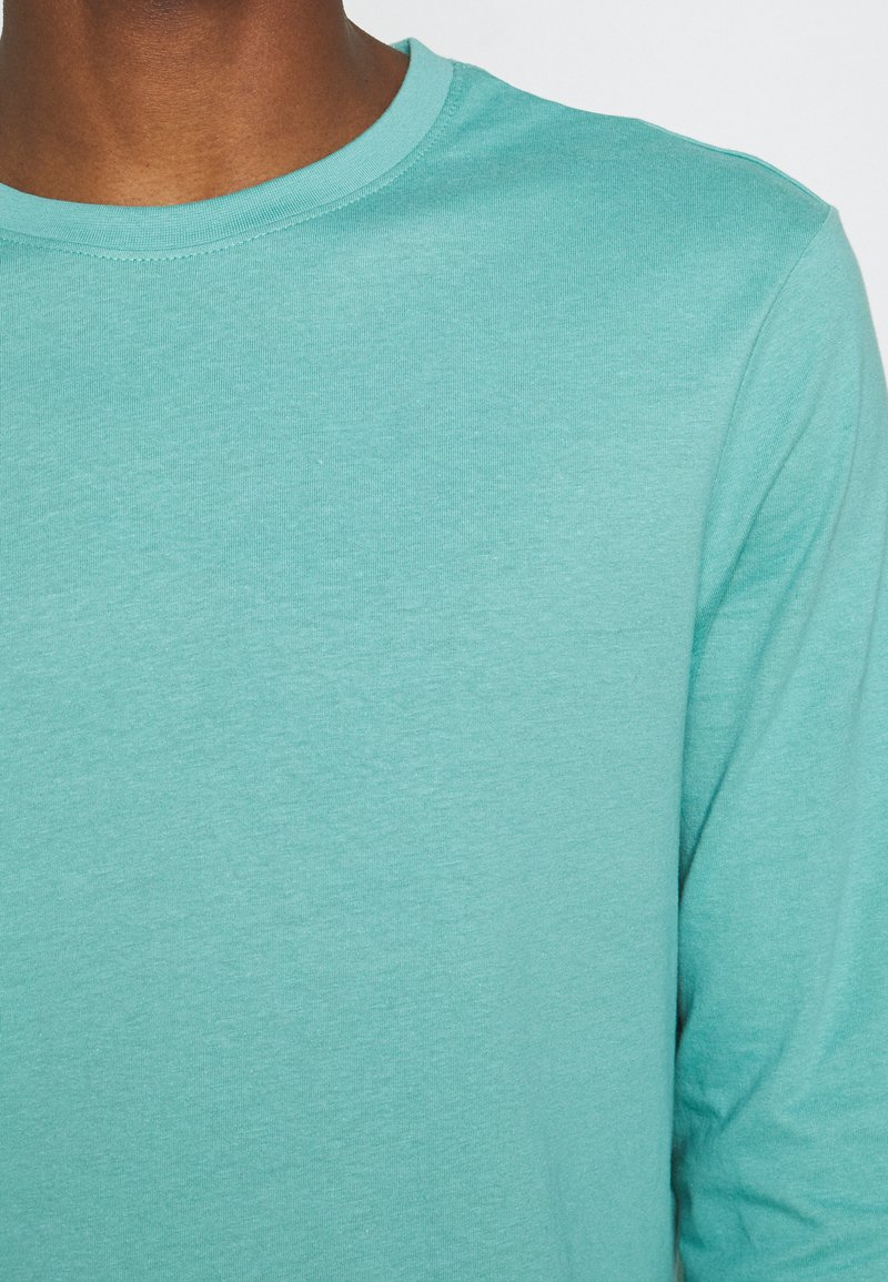 Türkises Langarm-T-Shirt, aus weicher Baumwolle, mit Rundhalsausschnitt und glatter Textur. Keine sichtbaren Muster oder Akzente.