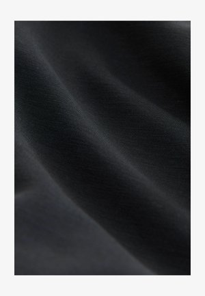 Svart tyg med en slät, jämn textur, som uppvisar en lätt lyster och subtila variationer i färg och ljus över ytan.