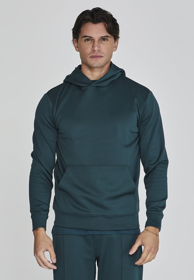 Sudadera azul oscuro hecha de una tela suave y lisa. Cuenta con un bolsillo tipo canguro en la parte frontal y una capucha ajustable con cordón. Diseño entallado con puños de canalé.
