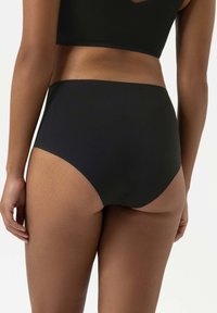 Slip bikini neri a vita alta realizzati in tessuto morbido, con design senza cuciture e copertura moderata sul retro.