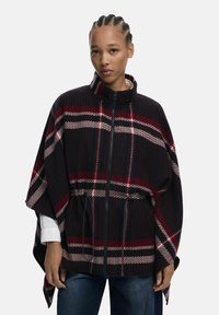 Kariertes Poncho aus Wollmischung mit hochgeschlossenem Kragen, Reißverschluss und elastischem Bund. Farben sind Schwarz, Rot und Creme mit strukturierter Oberfläche.