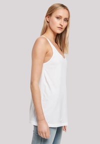 White, sleeveless tank top made of cotton. Features a V-neck design, lightly fitted shape, and smooth texture.