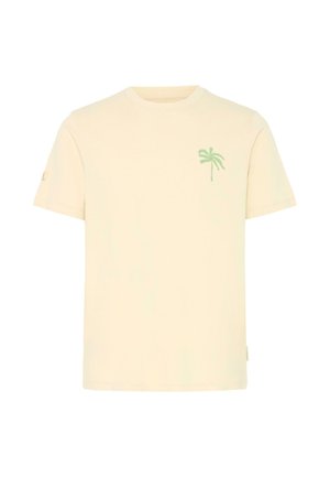Camiseta beige de manga corta con un pequeño diseño de palmera verde en el pecho izquierdo y un logo en la manga izquierda.