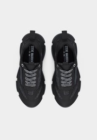 Paire de baskets Steve Madden noires et grises avec semelles épaisses et lacets à motifs, vues de dessus sur un fond blanc.