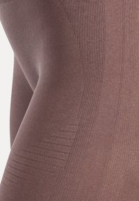 Collants marron opaques avec un tricot texturé, présentant des côtes verticales sur les côtés et une finition lisse, mettant l'accent sur le confort et la flexibilité.