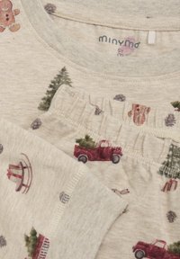 Beige katoenen pyjamastel met bedrukte patronen van rode vrachtwagens, bomen, peperkoekmannetjes en sneeuwvlokken. Elastische tailleband en zachte textuur.