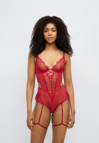 Κόκκινο κορμάκι από δαντέλα με διαφανές σχέδιο, κυματιστά άκρα και κοψίματα στα πλευρά. Περιλαμβάνει ρυθμιζόμενους ιμάντες και προσθήκες ζαρτιέρων.