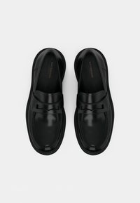 Sorte lær loafers med rund tå, sløyfe detalj på reimen, polstret såle og kontraststing langs sålen.