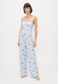 Jasnoniebieski zestaw odzieży domowej składający się z topu na ramiączkach i spodni szerokich nogawkach, ozdobiony kwiatowymi i ciastkowymi wzorami, uszyty z miękkiego materiału.