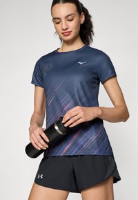 Tumed sportshirt lilla diagonaalsete triipudega ja palmigraafikuga; koos mustade lühikestega. Kasutaja hoiab musta veepudelit.