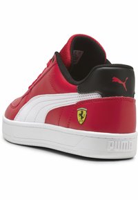 Sneakers sintetice roșii cu o dungi albă, călcâi negru și logo-ul Ferrari. Prezintă o textură netedă și un guler căptușit pentru confort.
