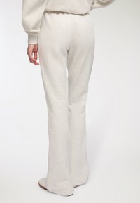 Jasnoszare dzwonowate spodnie dresowe o miękkiej fakturze, elastycznym pasie i minimalnej ilości szwów, charakteryzujące się luźnym krojem i dłuższą długością.