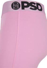 Primo piano di leggings sportivi rosa con una fascia larga in vita etichettata con la scritta "PSD" in lettere nere e logo.