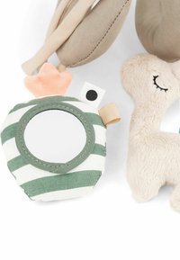 Stoffspielzeug mit einem runden, grün-weiß gestreiften Spiegel mit einem weichen peachfarbenen Element, neben einem beigen Plüschtier mit einem Lächeln.