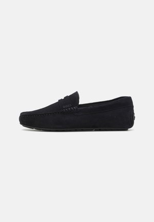 Marineblauwe suede instappers met een gestructureerde bovenkant, voorzien van gestikte details op de voorvoet en een rubberen zool voor grip.