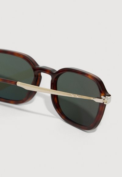Sunglasses iz mačamore z zelenimi lečami, z zlatim kovinskim poudarkom na ročajih in kvadratnim okvirjem.