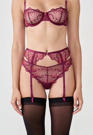 Burgunderfarbener Spitzenwäsche-Set mit einem leicht transparenten BH mit floralen Mustern, passendem Strumpfband und schwarzen Strümpfen mit Satin-Akzenten.
