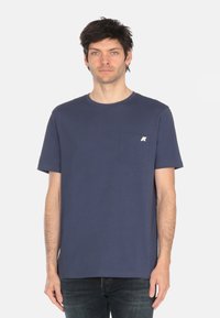 T-shirt in cotone blu navy con scollatura rotonda, maniche corte e taschino sul petto con logo a contrasto. Texture liscia.