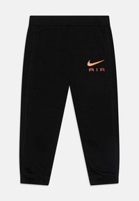 Black Nike sweatpants made of soft fabric, featuring a tapered fit, elastic waistband, and orange "AIR" logo on the left thigh.