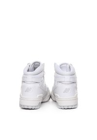 Białe wysokie trampki wykonane ze skóry i siateczki, z teksturowaną powierzchnią, wyściełanym kołnierzem oraz logo New Balance na pięcie.