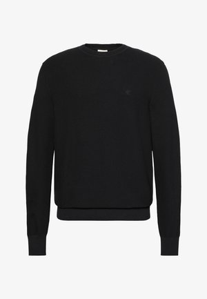 Fekete kötött hosszú ujjú pulóver, kerek nyakkivágással, bordázott mandzsettákkal és szegéllyel, kis, diszkrét logóval a bal mellrészen.