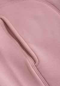 Rosa stoff med en glatt tekstur, som har en synlig søm og en glidelåslomme. Designet er minimalistisk og funksjonelt.