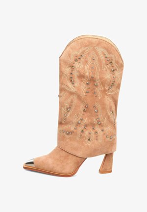 Stivale alla caviglia in suede beige chiaro, con accenti metallici, punta appuntita e motivi decorativi di perline sul gambale, dotato di tacco a blocco.