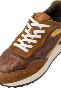 Sneaker in suede e mesh marrone con lacci crema, linguetta imbottita e suola in gomma. Presenta accenti marroni e una superficie texturizzata.