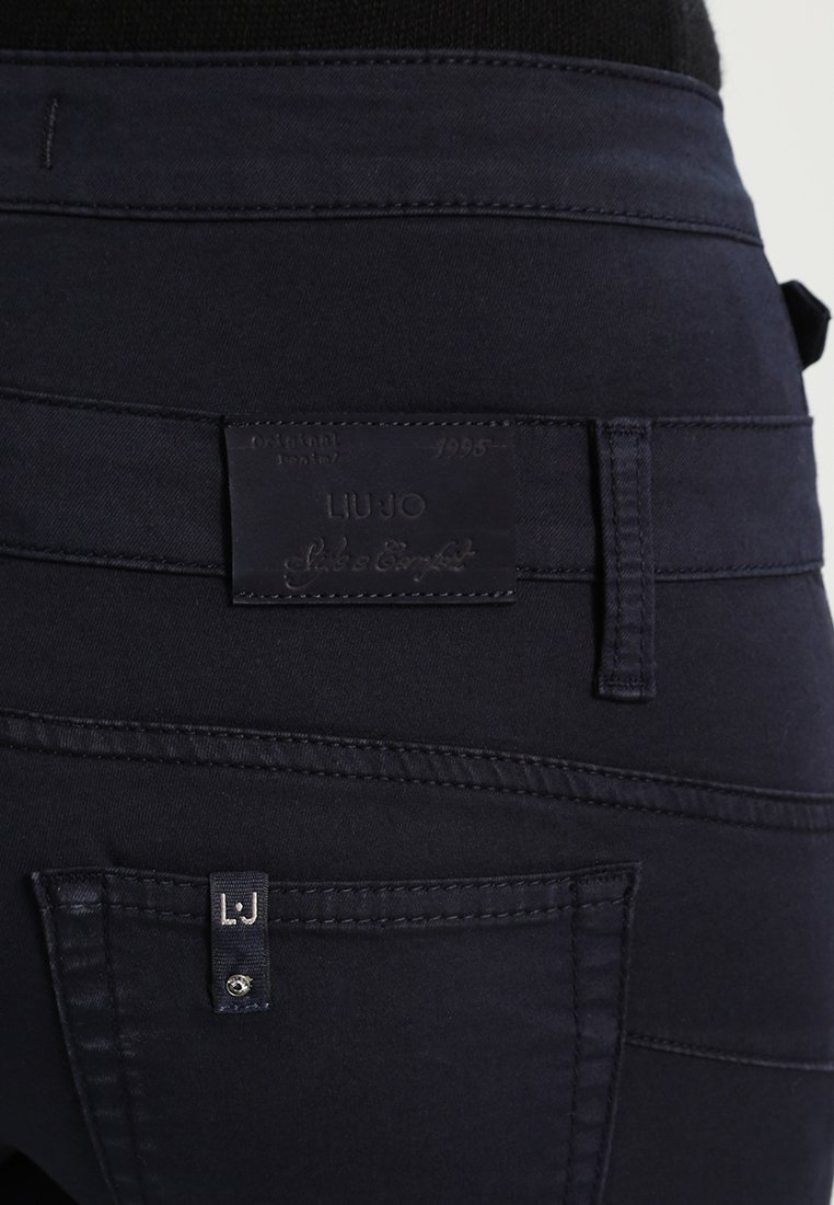 Dunkelblaue Denim-Jeans mit einem Lederetikett mit "LIUJO" am hinteren Bund, genähten Details und einem kleinen Markierungsetikett an der Tasche.