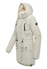 Jasnobeżowa parka z fakturowanym, ocieplanym kapturem, sznurkami ściągającymi i wieloma zasuwanymi kieszeniami. Zawiera czarne akcenty i ściągnięcie w talii.