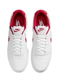 Scarpe da ginnastica bianche Nike con accenti rossi. Presentano dettagli perforati, lacci piatti e il marchio sulla linguetta e sul lato. La fodera interna è rossa.