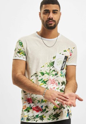 Hvid t-shirt med et blomster mønster i pink og grøn, med en lomme og korte ærmer med en lys grå kant.