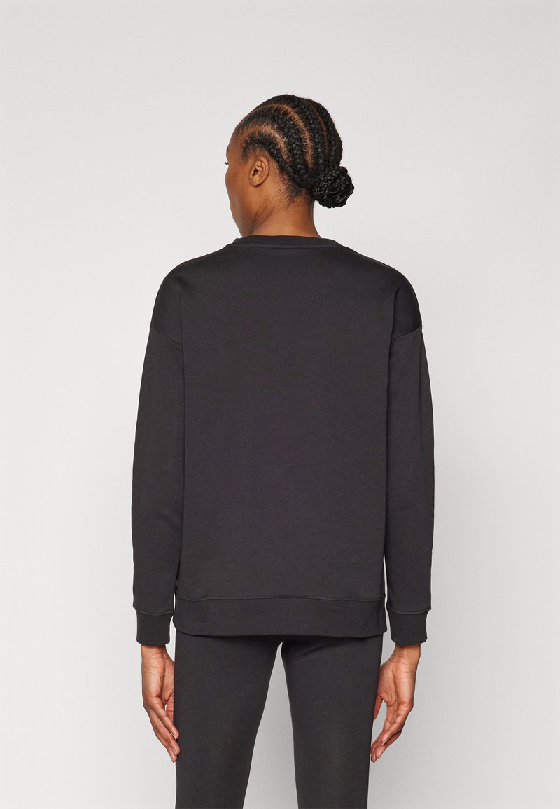 Schwarzer Sweatshirt aus weichem Stoff mit lockerer Passform, gerippten Bündchen und Saum sowie glatter Textur; getragen mit passenden schwarzen Unterteilen.