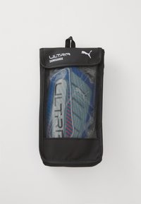 Sort mesh pung der holder blå og sølv Puma Ultra skinnebeskyttere med røde accenter, mærket til sportbeskyttelse.