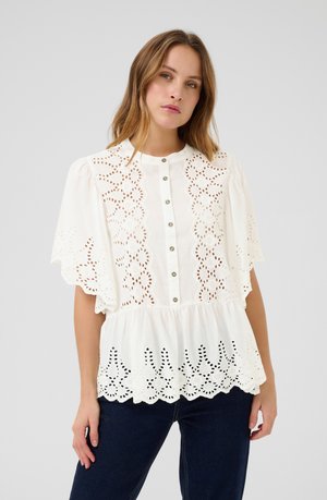 Blusa blanca con detalles de bordado inglés floral, mangas cortas acampanadas, cierre de botones en la parte delantera y un dobladillo de peplum fruncido.