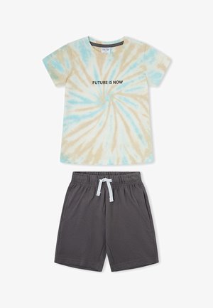 Camiseta de manga corta tie-dye con texto "FUTURE IS NOW" en negro, combinada con pantalones cortos de cintura elástica gris oscuro con cordón blanco.