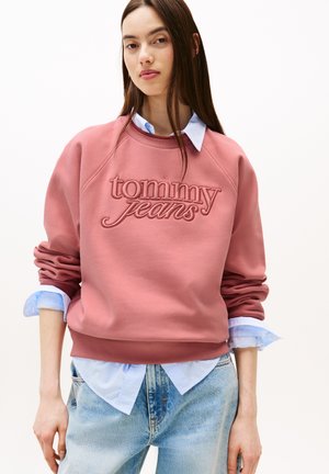 Pink sweatshirt with "tommy jeans" in raised embroidery. Ribbed collar and hem, paired with a light blue checkered shirt underneath. Denim jeans.