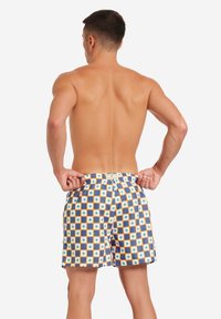 Costumi da bagno da uomo con un motivo a quadrati e diamanti nei colori blu, arancione e bianco. Realizzati in tessuto leggero con vita elastica.