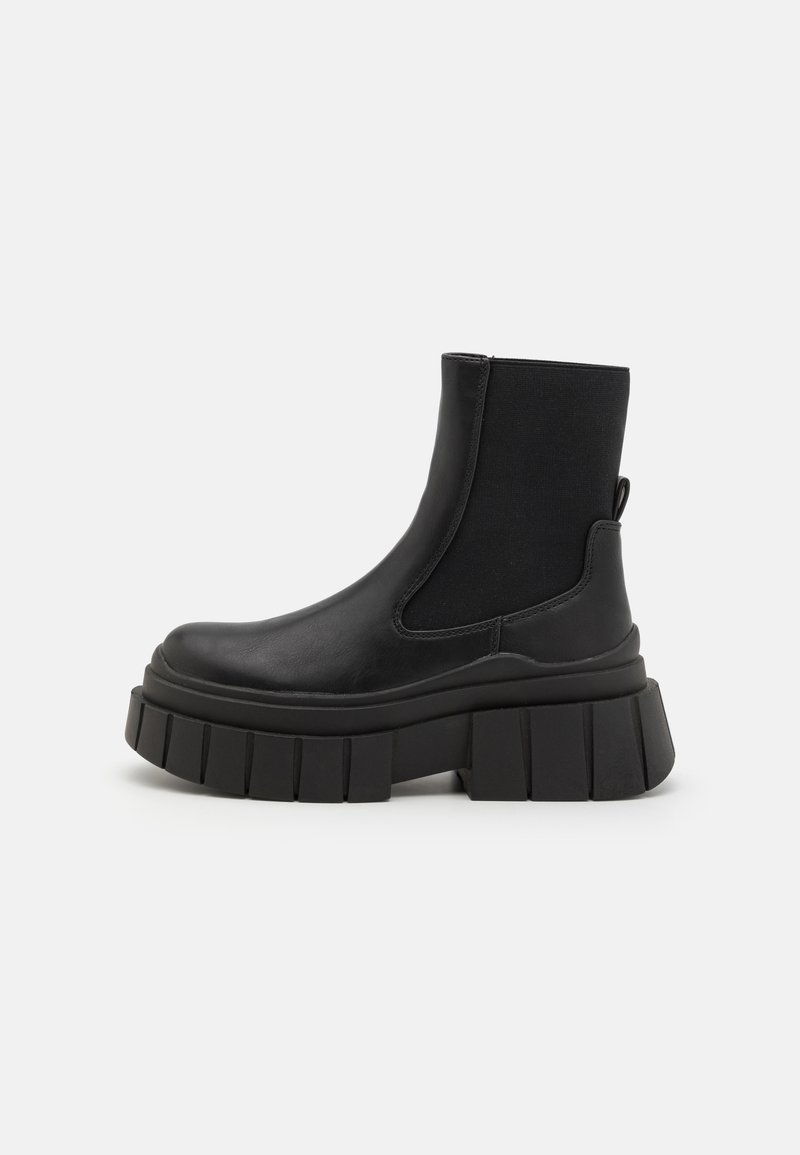 Black ankle boots made of smooth leather with elastic side panels, a chunky platform sole, and a textured tread design.