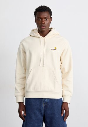 Beige hooded sweatshirt features a front pocket, adjustable drawstrings, and a small logo in yellow and red on the left chest.