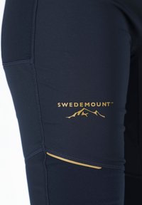 Leggings sportivi blu navy con logo dorato "SWEDEMOUNT" e grafica di montagna. Presentano cuciture piatte e un dettaglio a accentuazione laterale.