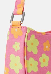 Růžová textilní taška s květinovým vzorem a zelenými a oranžovými akcenty. Obsahuje kovovou popruhovou sponu se švy.