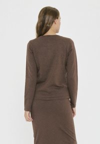 Brown long-sleeve top, made of soft fabric, featuring a relaxed fit, crew neckline, and hemline ending at the waist, plain texture.