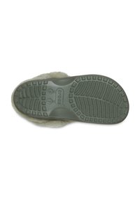 Crocs con una suela de goma verde claro, que presenta un patrón texturizado para el agarre y un suave forro de piel de color beige en la parte superior.